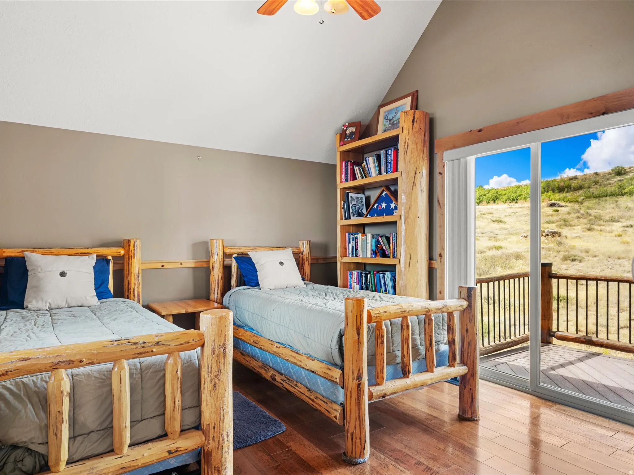 Wood-finish flooring, built-in shelving, vaulted ceiling, and sliding glass door to an exterior deck