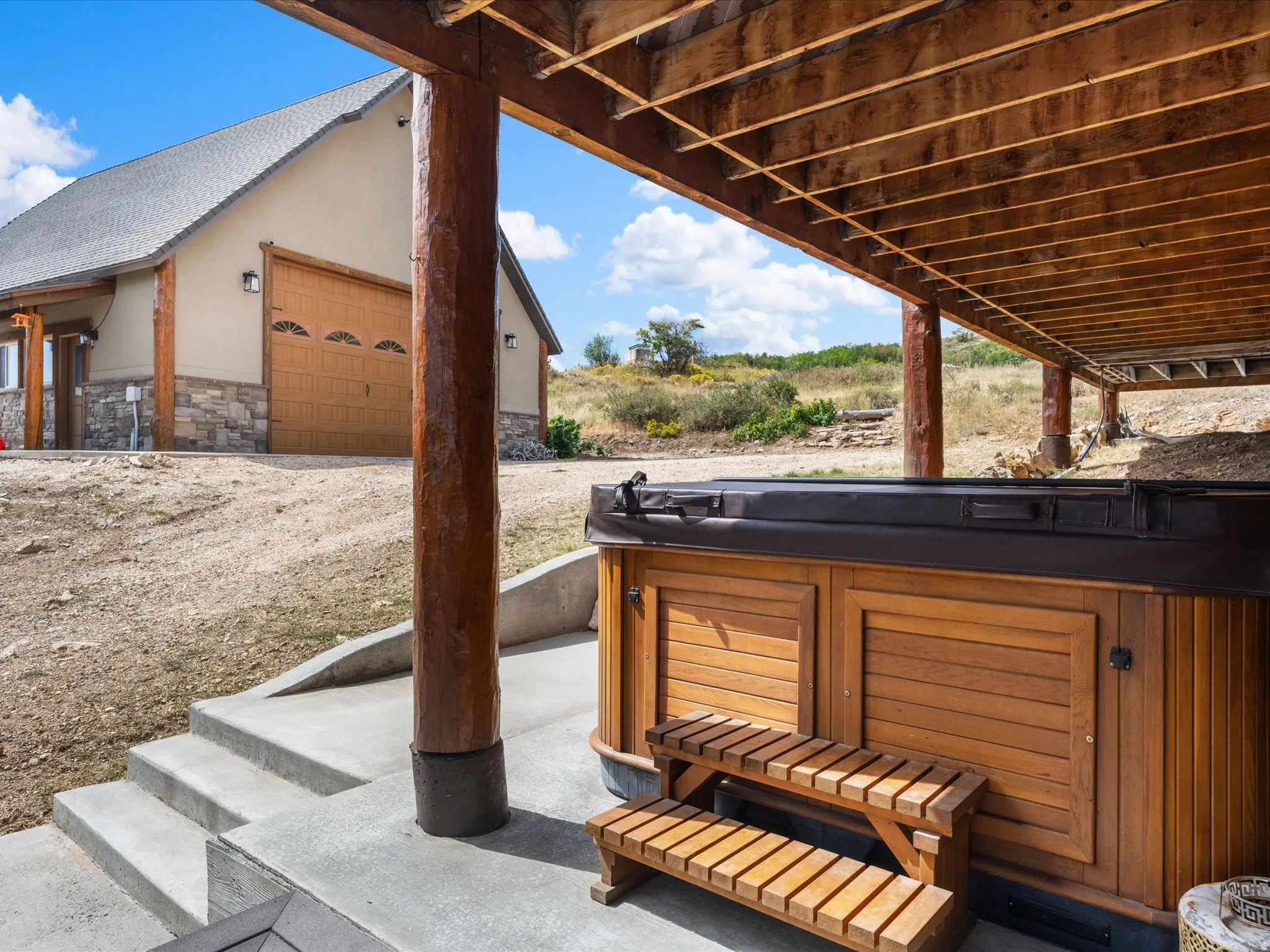 Hot tub with wood-finish exterior paneling and accompanying steps, situated on a concrete patio