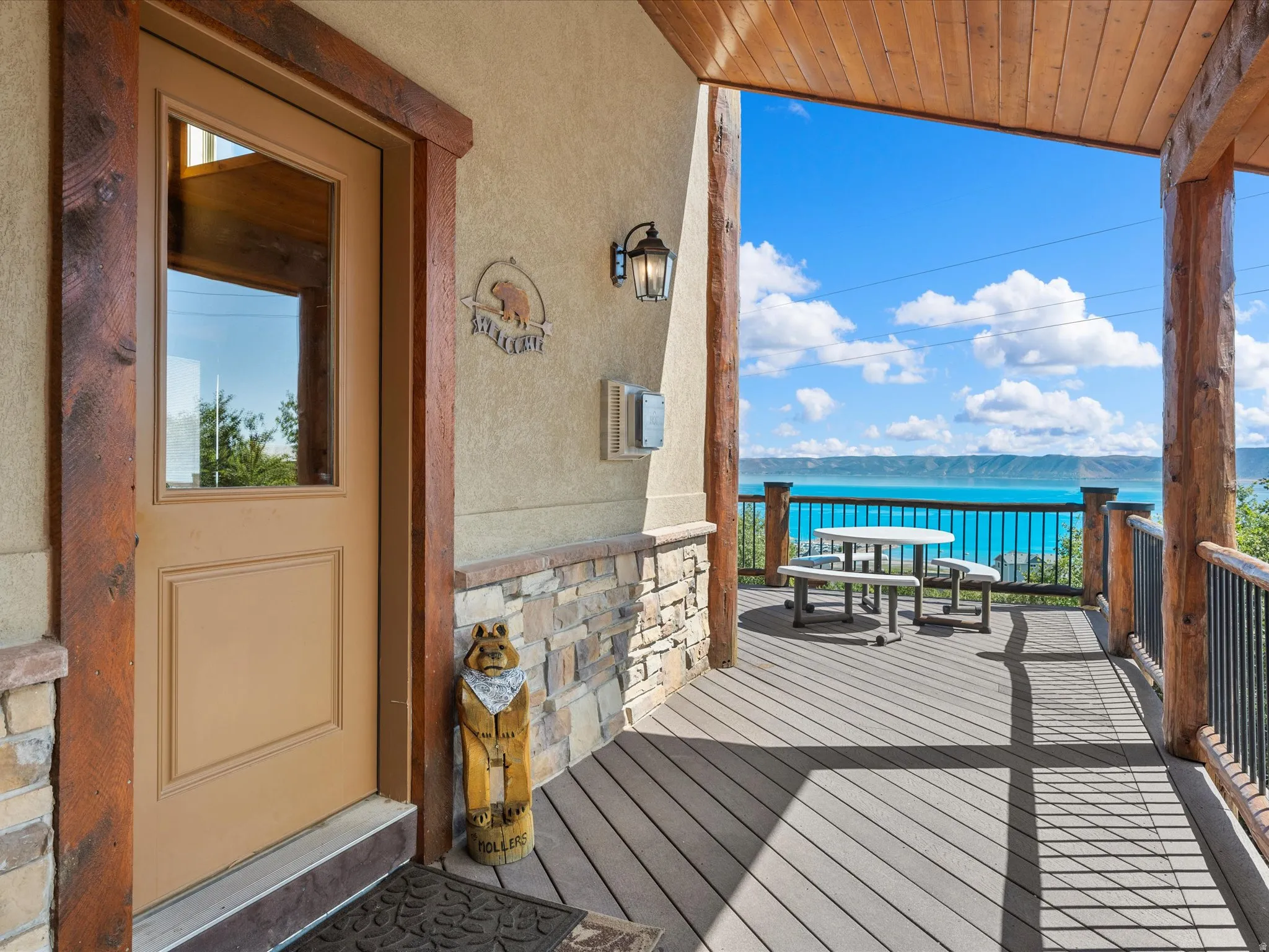 Expansive covered deck featuring wood-finish flooring, robust timber columns, and a metal railing