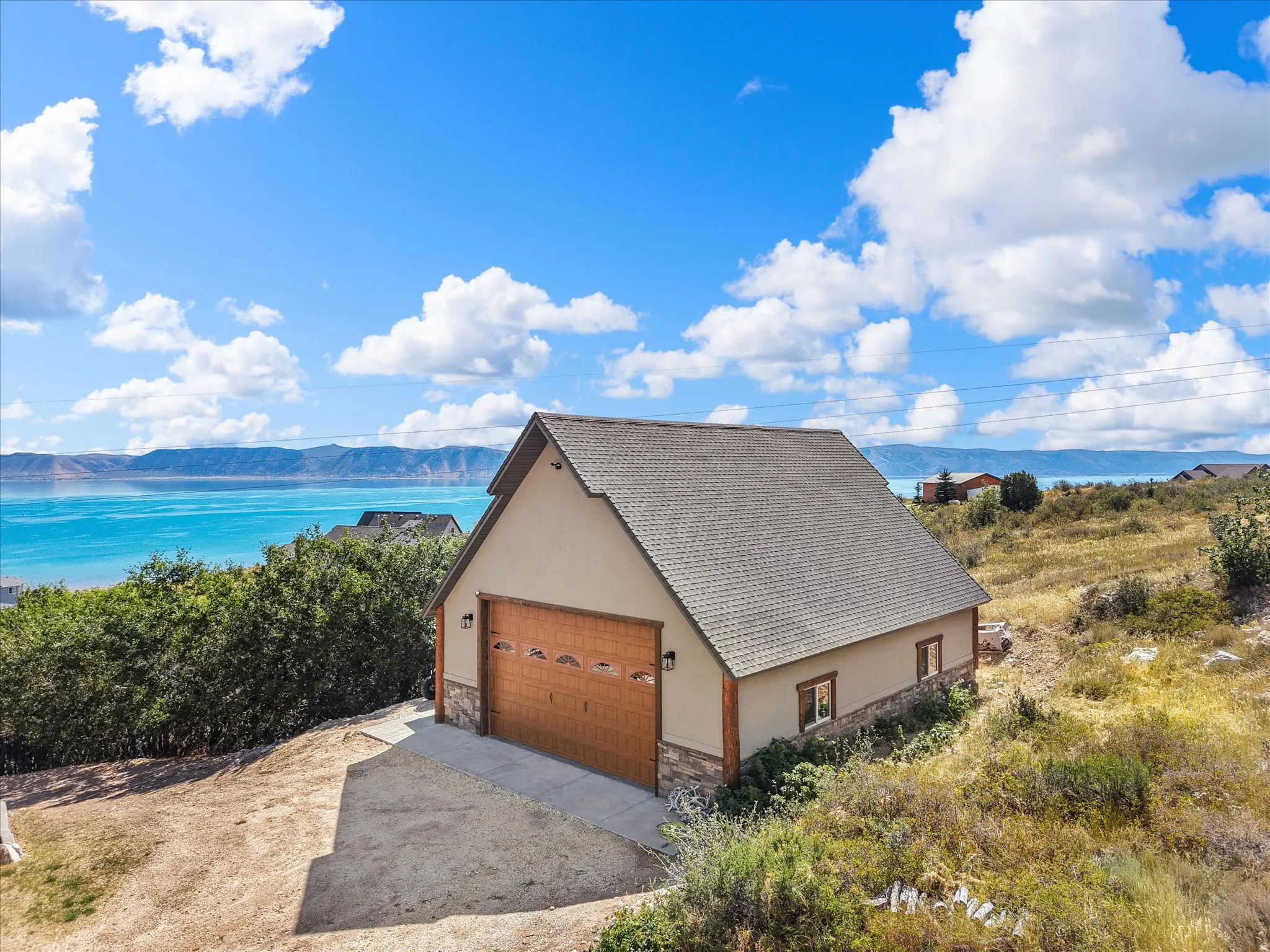 Detached structure with an attached garage, a composition shingle roof, stucco siding, and stone accents