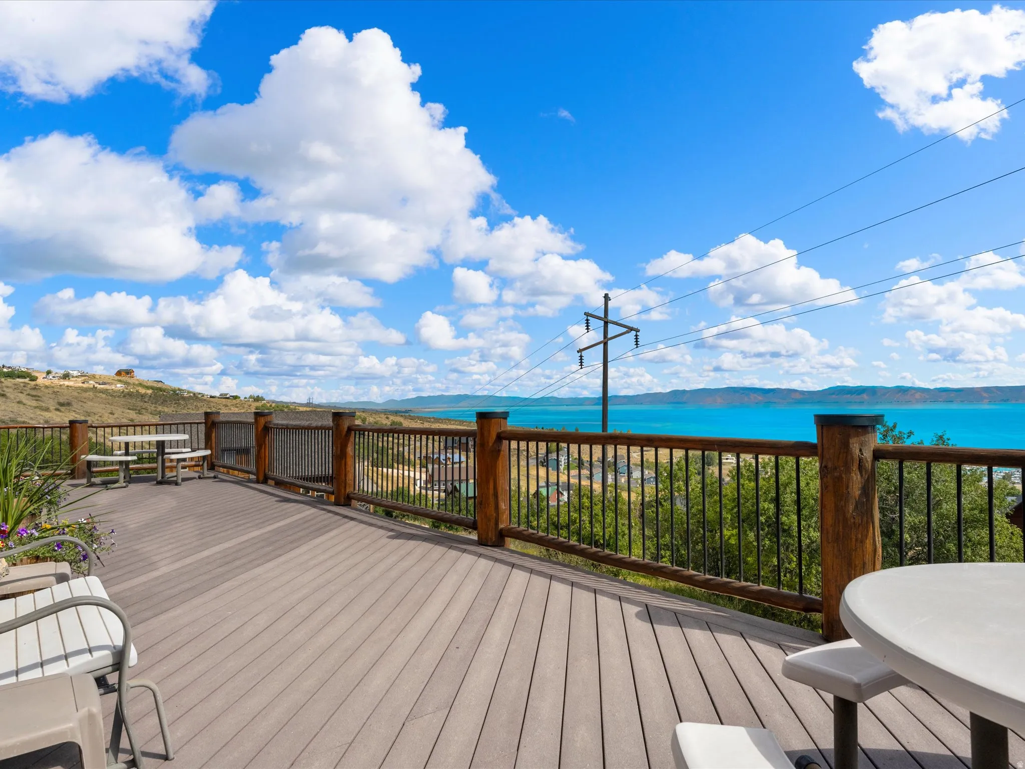 Expansive composite decking featuring a wood-finish railing, metal balusters, and panoramic water scenery