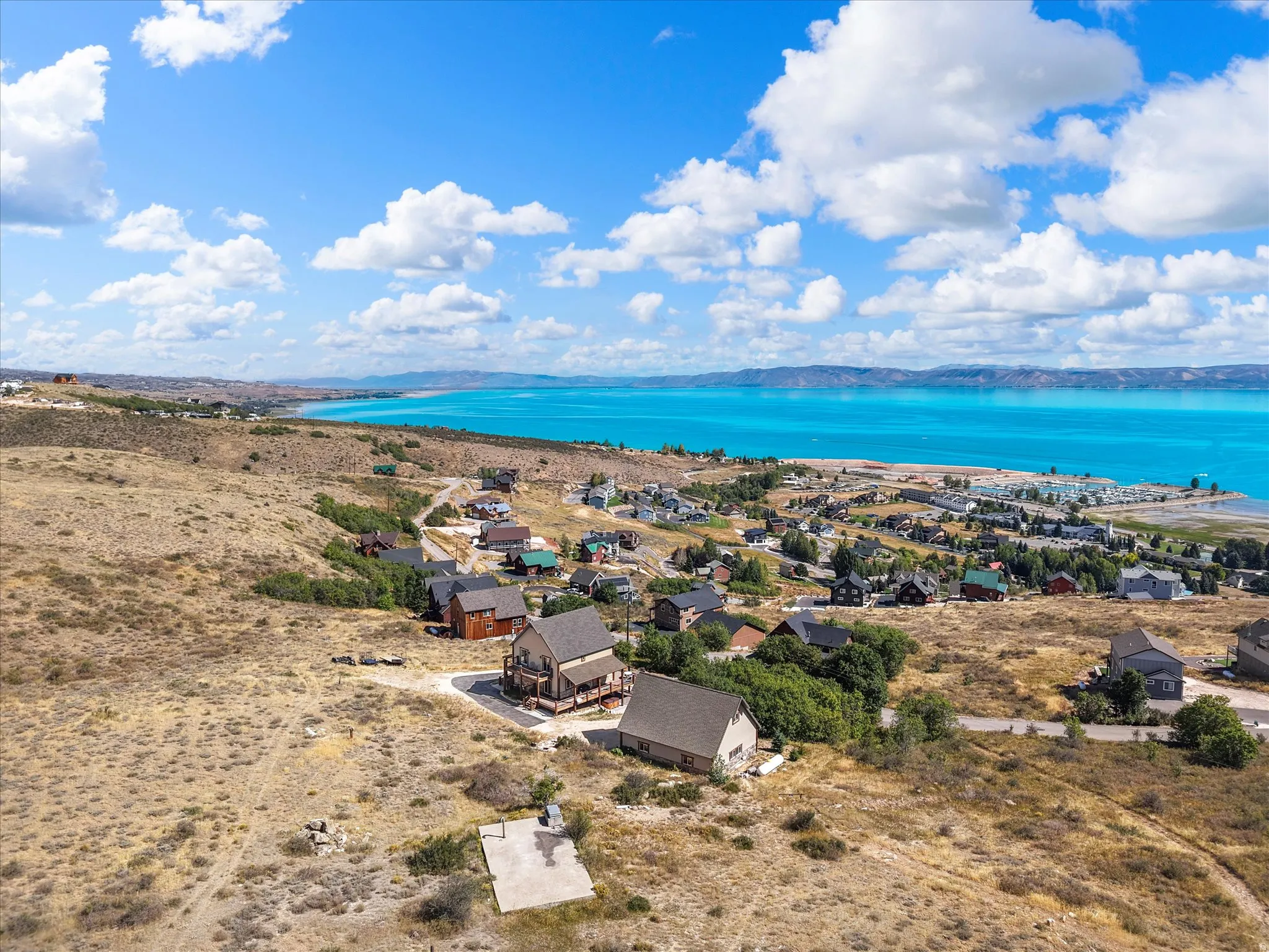 Expansive lake scenery with surrounding hillsides, multiple structures, and a concrete pad