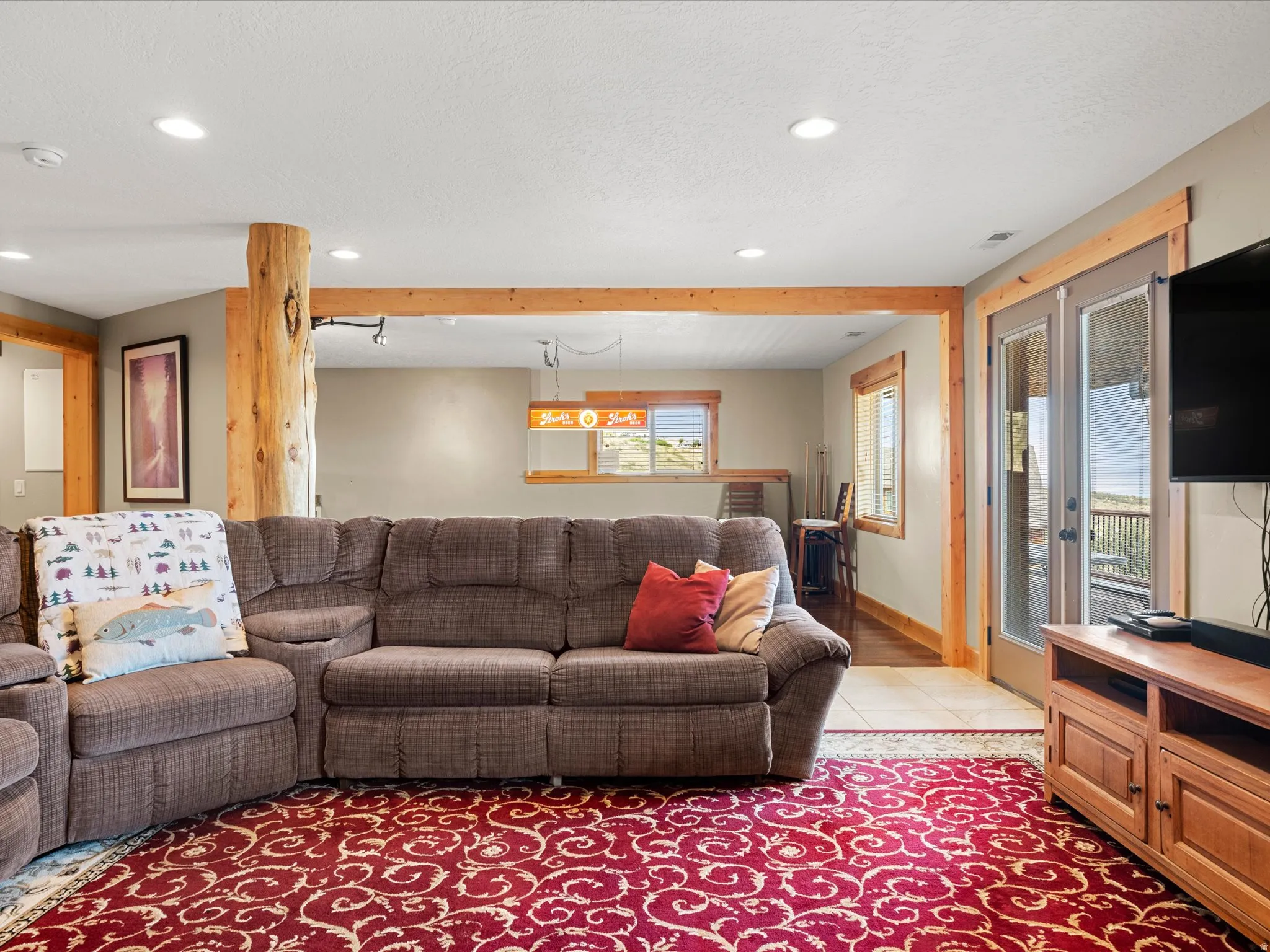 Recessed ceiling lighting, exposed timber structural elements, dual paned windows with wood trim, and a glass-paneled door