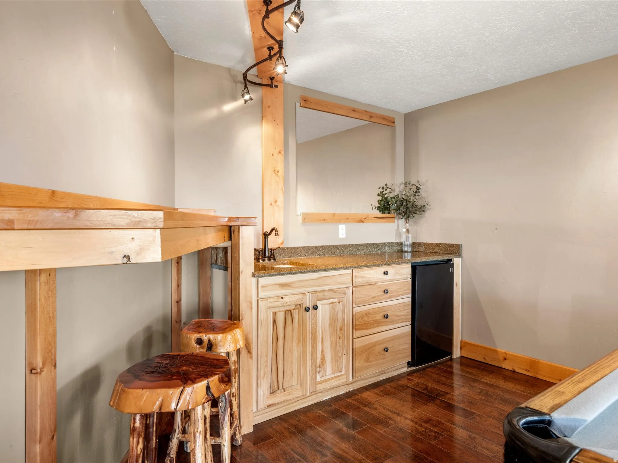 Wood-finish flooring with a custom-built wood bar and matching stools