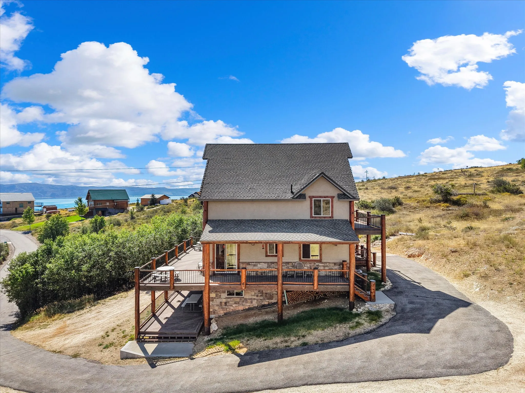 Multi-level exterior with extensive decking, stone accents, and a shingled roof