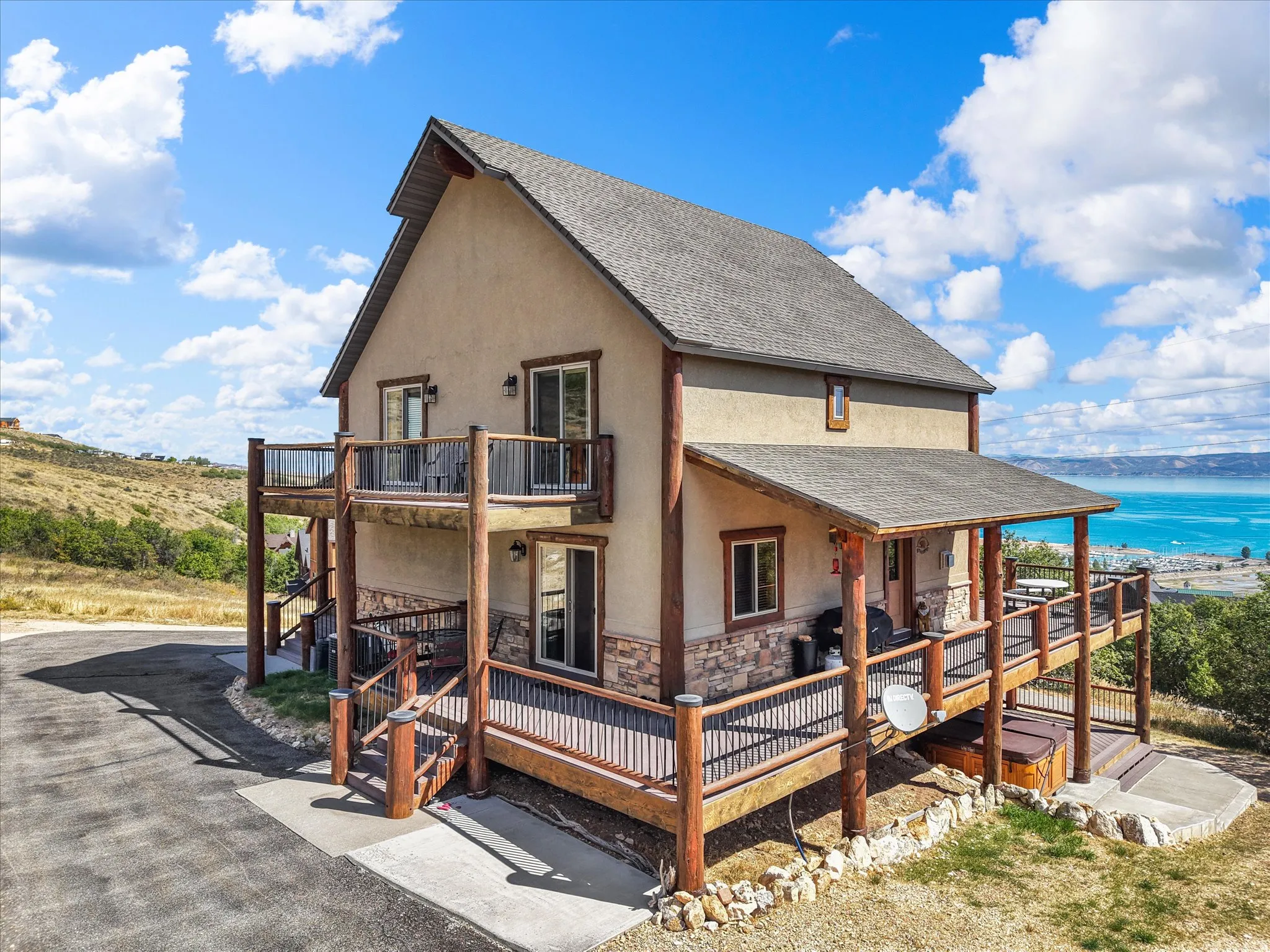 Two-story residence featuring a stucco exterior with stone accents, multiple outdoor decks, and a covered patio