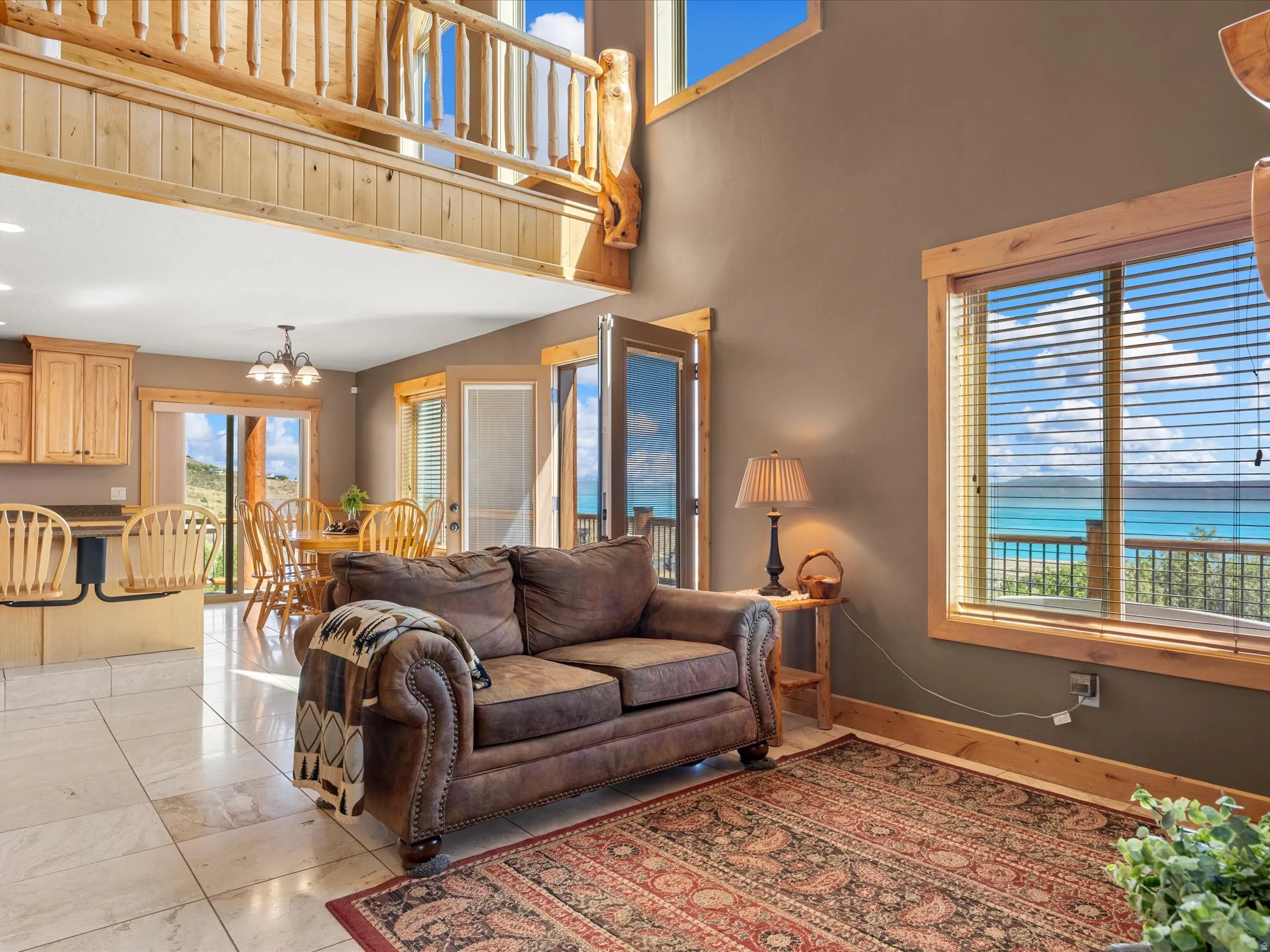 Open-concept living space with expansive windows, light wood-finish trim, and a high ceiling