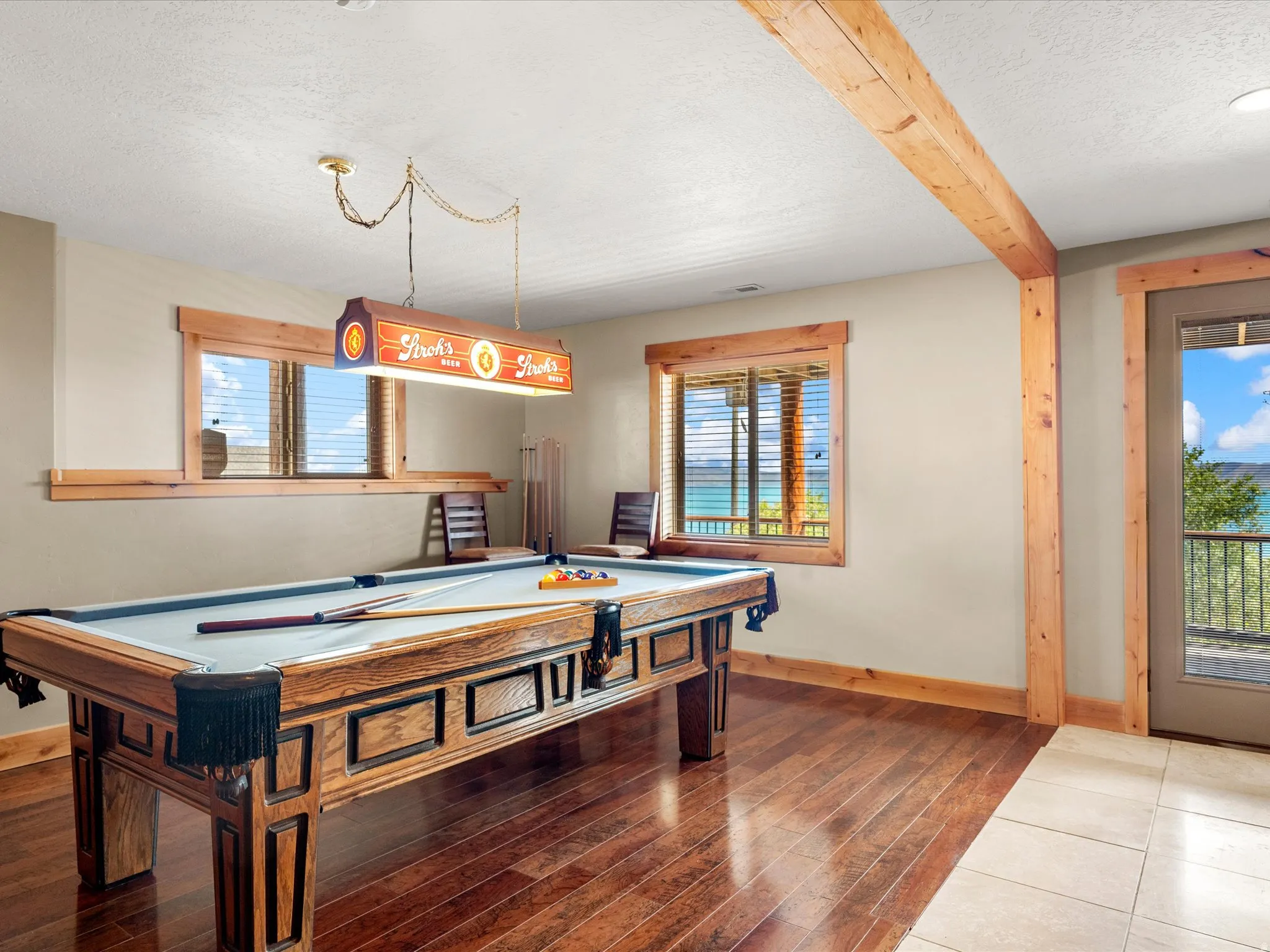 Wood-finish flooring, exposed wood beam, wood-trimmed windows, and wood-trimmed door