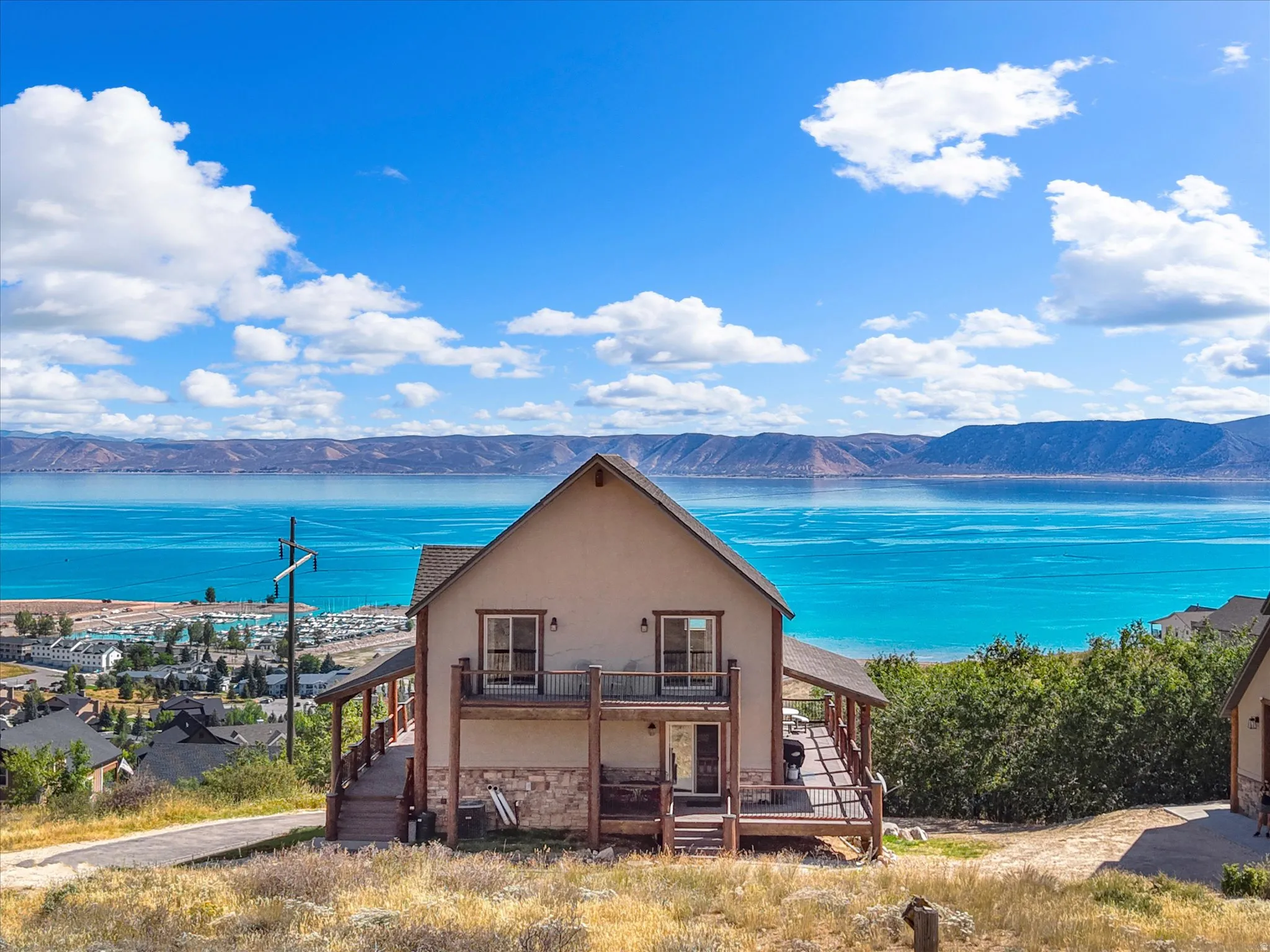 Two-story residence with a stucco exterior, multiple covered decks, and a balcony