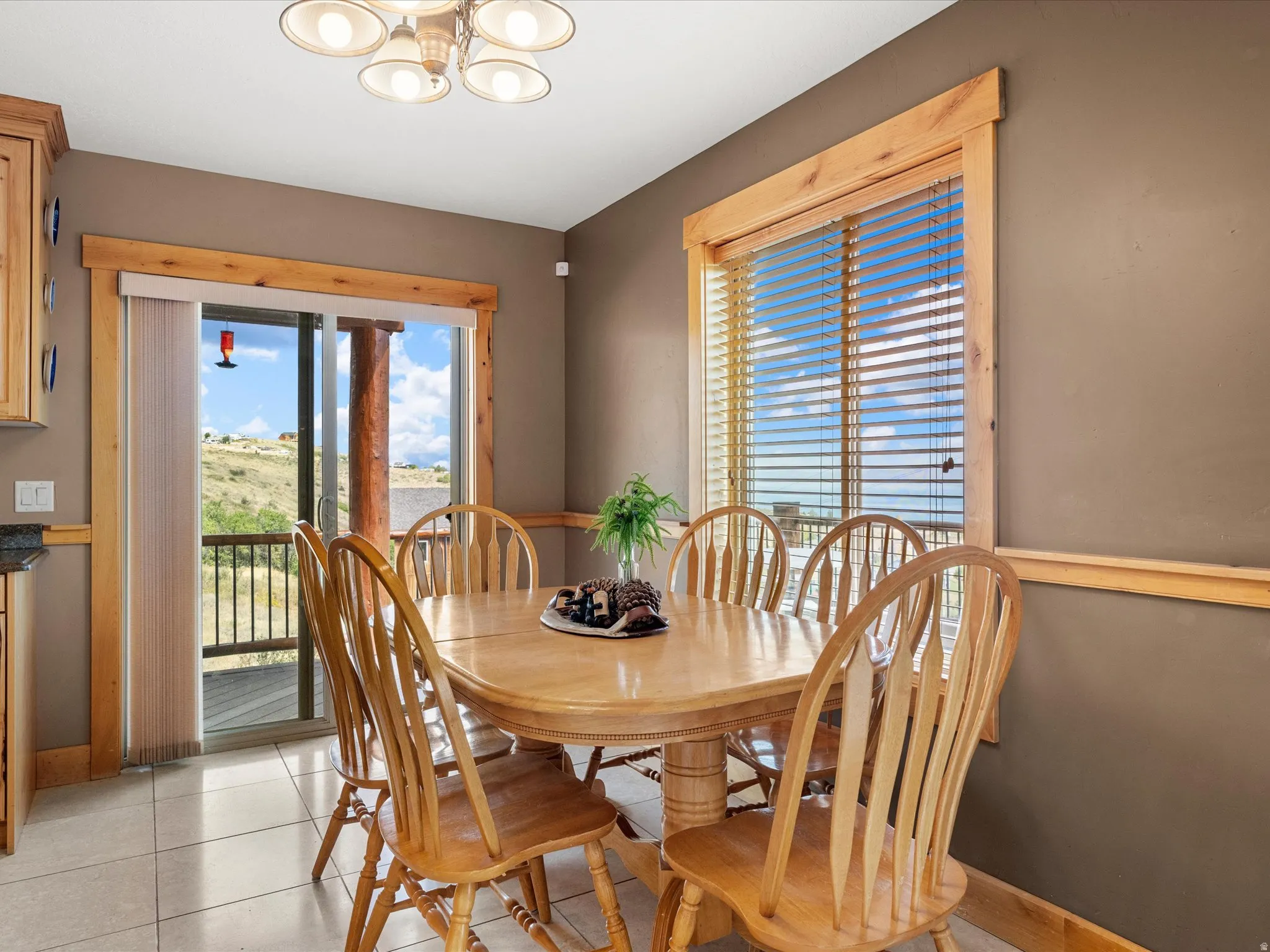 Sliding glass door to exterior, tiled flooring, wood-finish window trim, wood-finish cabinetry, and a ceiling-mounted light fixture