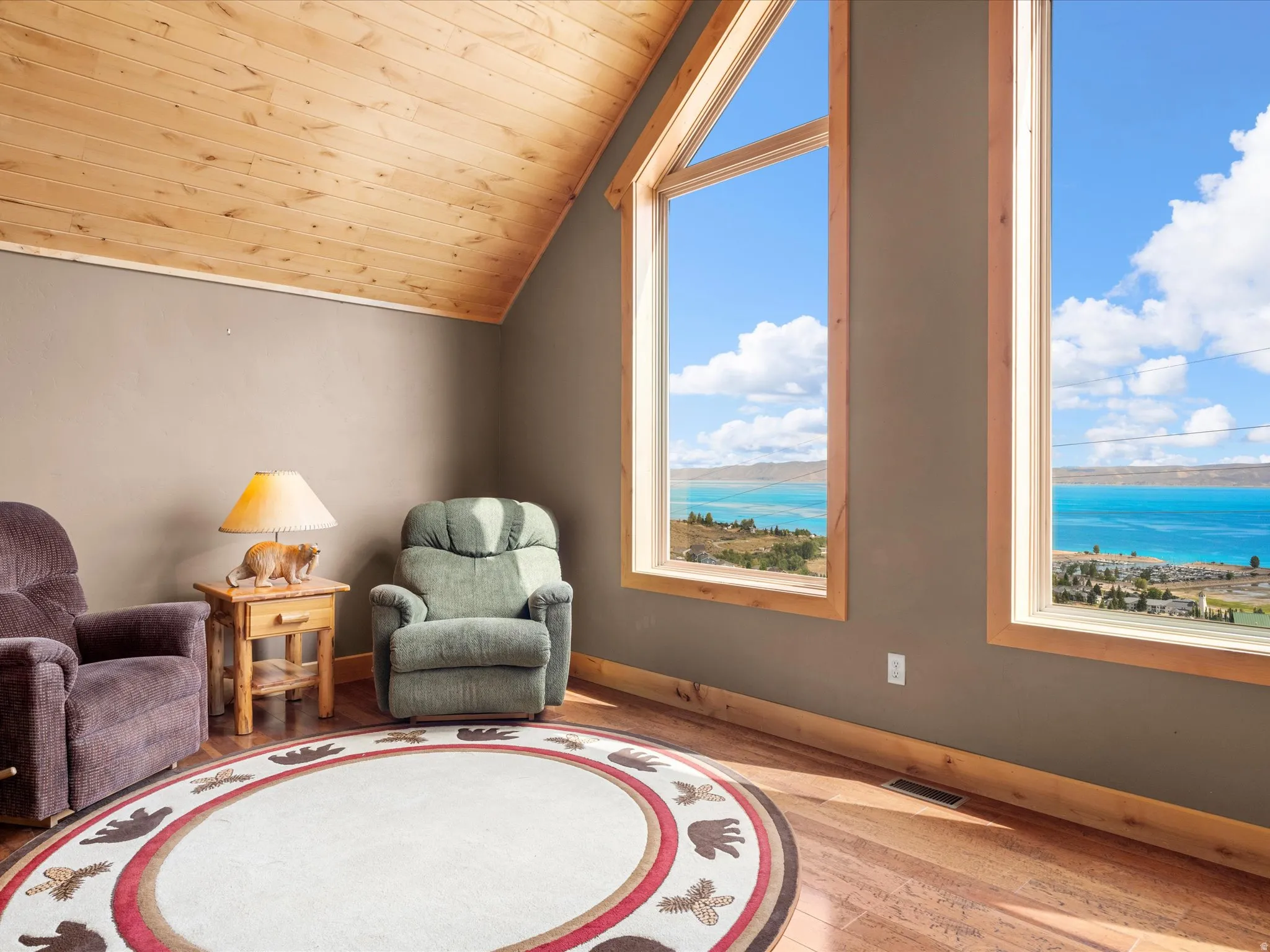 Vaulted wood-finish ceiling, wood-frame windows, wood-finish flooring, and expansive water scenery