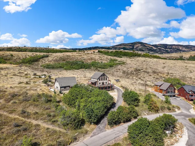 Property featuring a multi-level deck, a gravel driveway, and a natural, unlandscaped yard