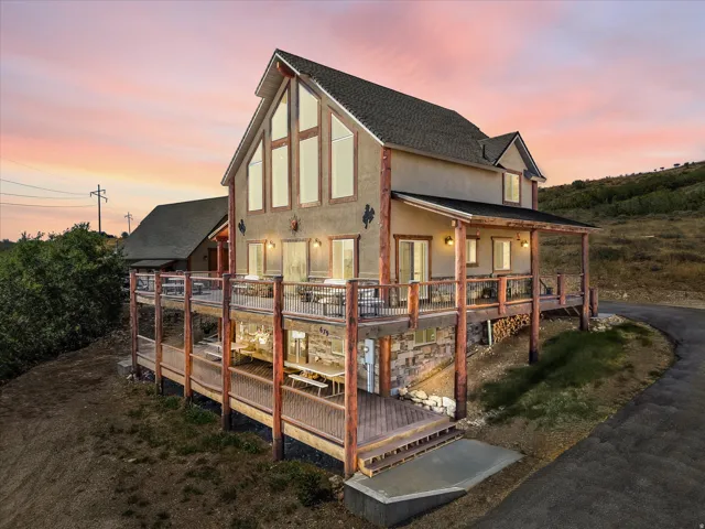 Multi-level outdoor decking, prominent A-frame window design, exterior stone accents, covered outdoor patio, and a sloped asphalt driveway
