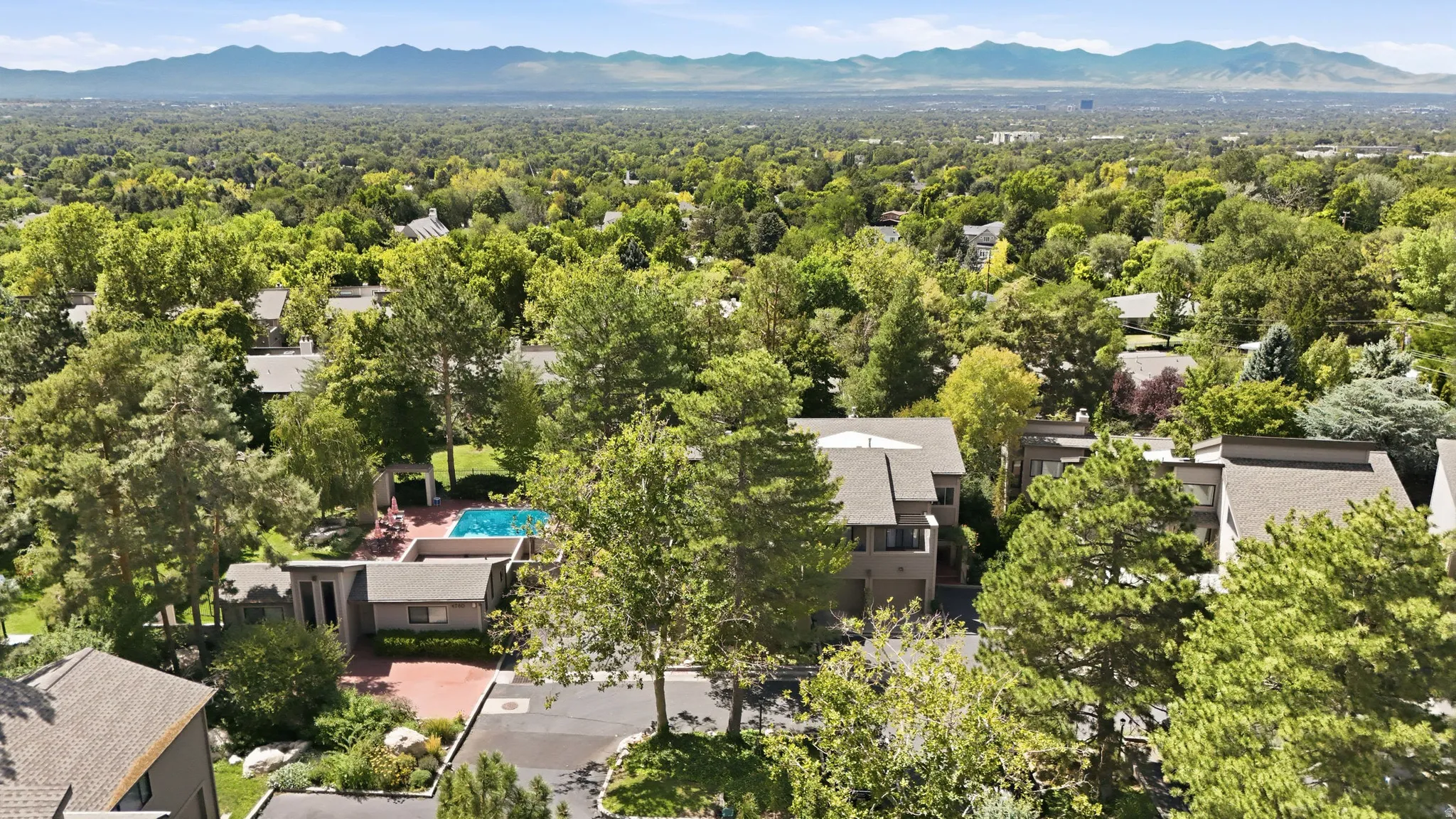 Residential property featuring multiple structures, a swimming pool, and a paved driveway