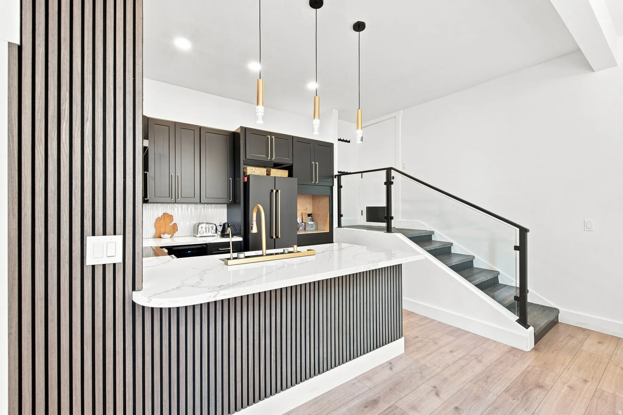 Modern kitchen with dark cabinetry, white quartz countertop, and gold-finish fixtures