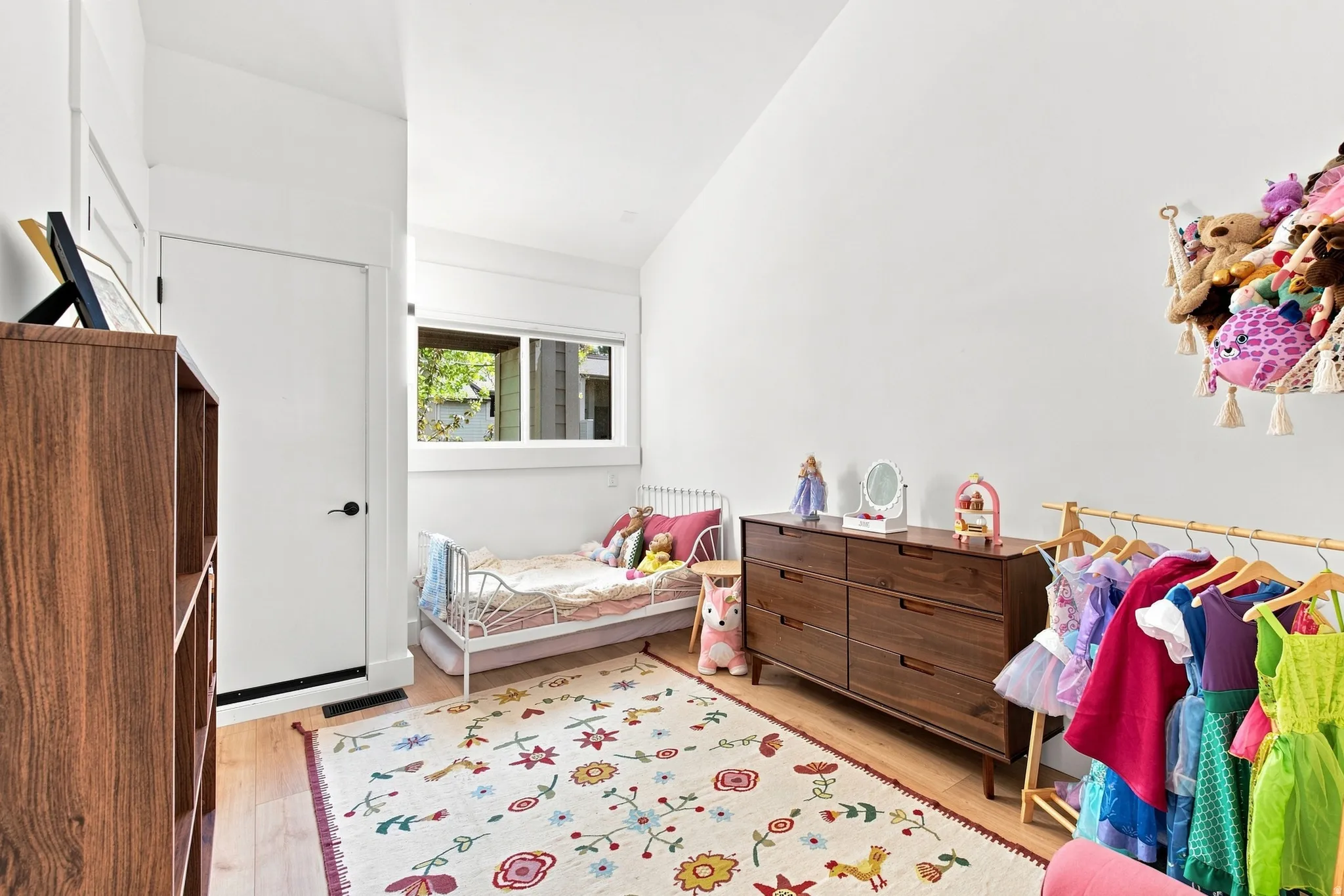 Sloped ceiling, hard surface flooring, white interior walls, white trim, and a built-in window