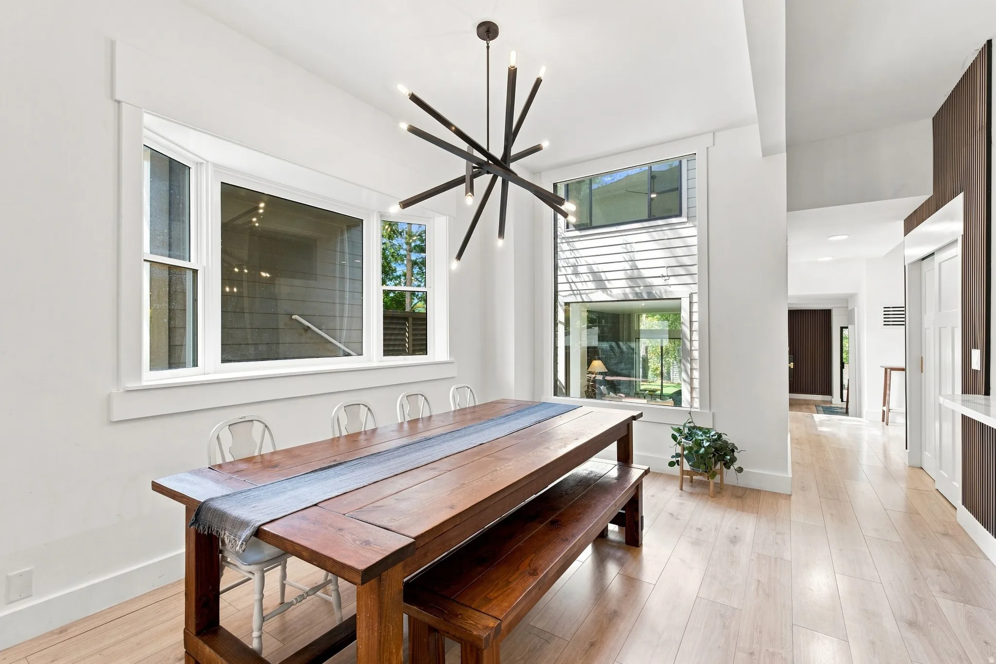 Bright interior featuring light wood-finish flooring, white walls, and a modern chandelier