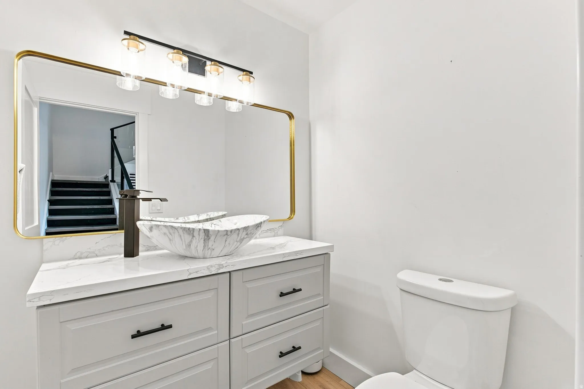 Light gray vanity with black hardware, white countertop, and a marble-finish vessel sink