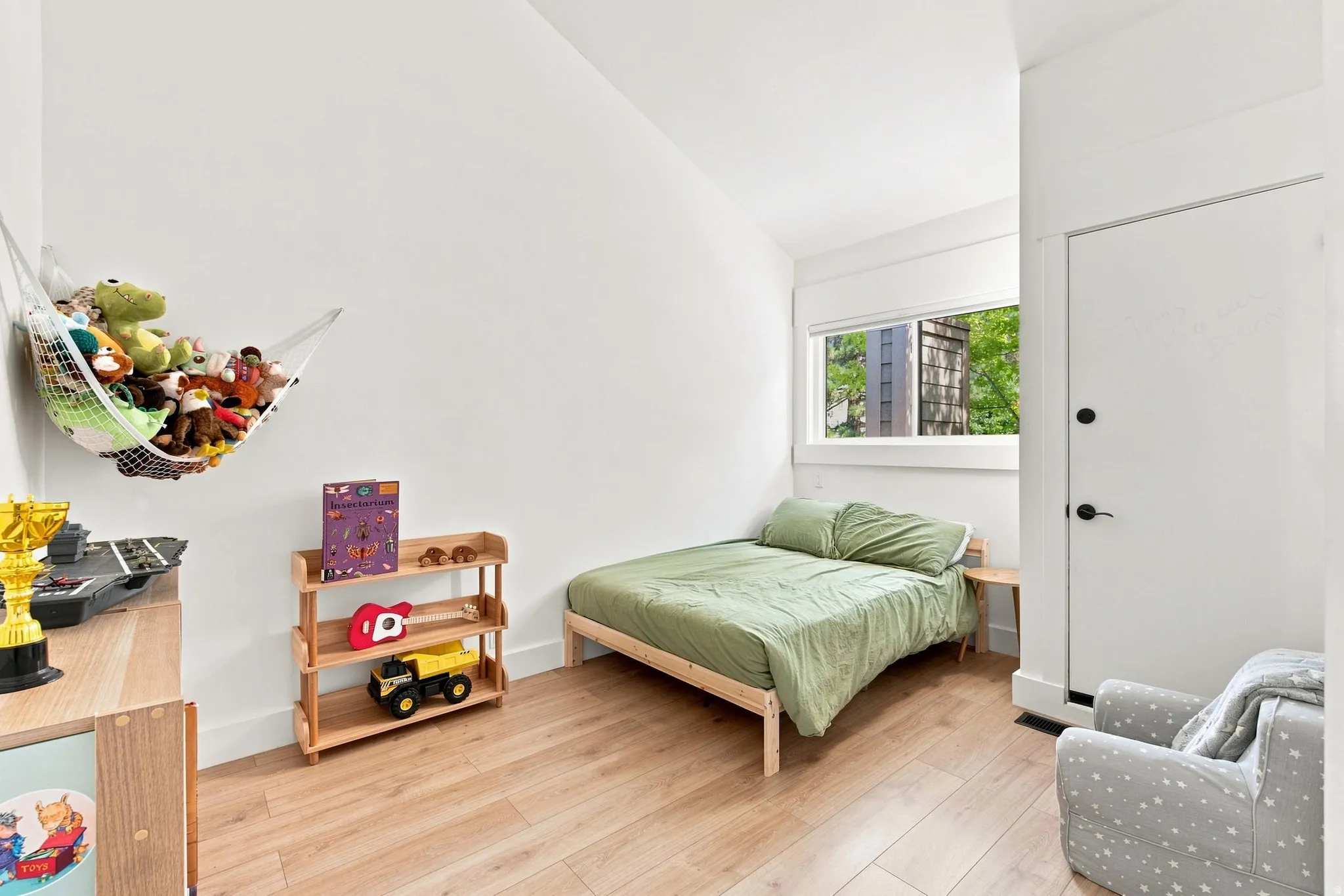 Light wood-finish flooring, white walls, and a large window providing natural light