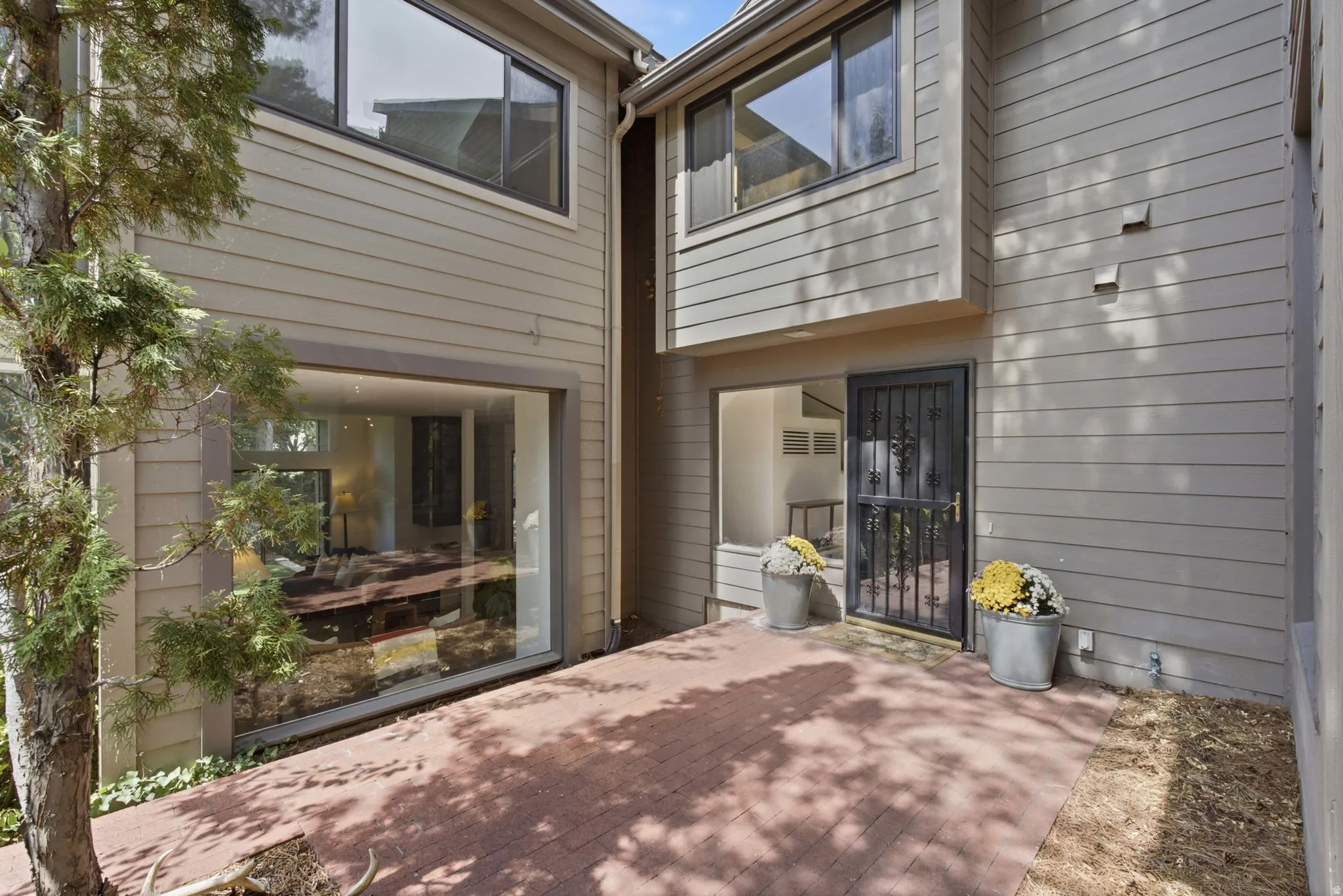 Exterior featuring horizontal siding, a red brick-patterned patio, a security screen door, and large picture windows