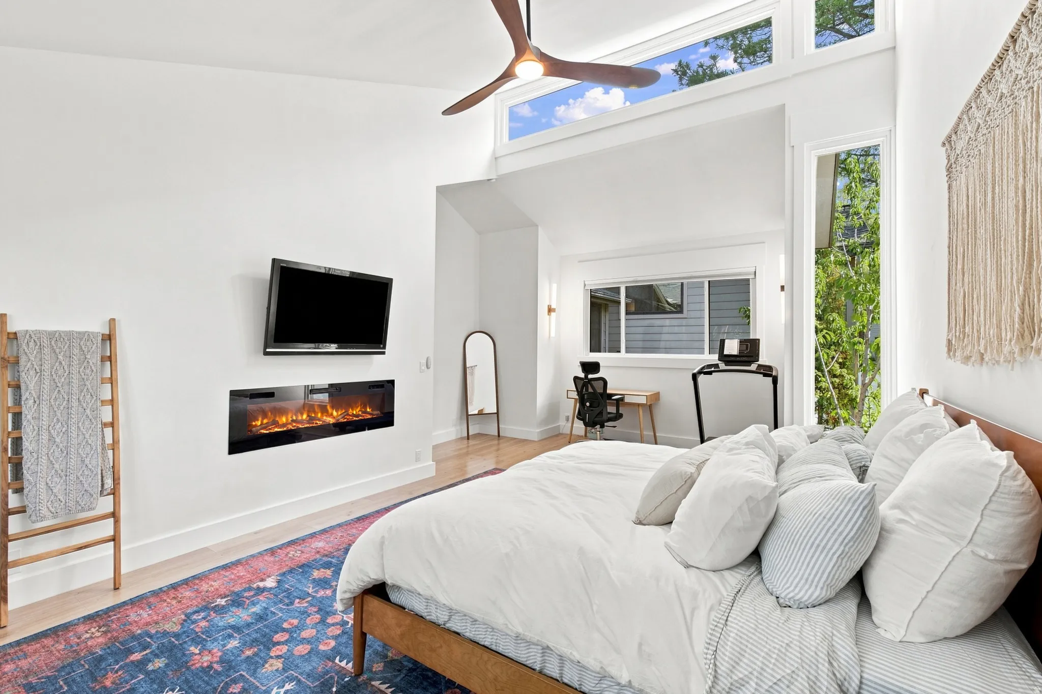 Vaulted ceilings with clerestory windows, built-in electric fireplace, wood-finish flooring, and a ceiling fan