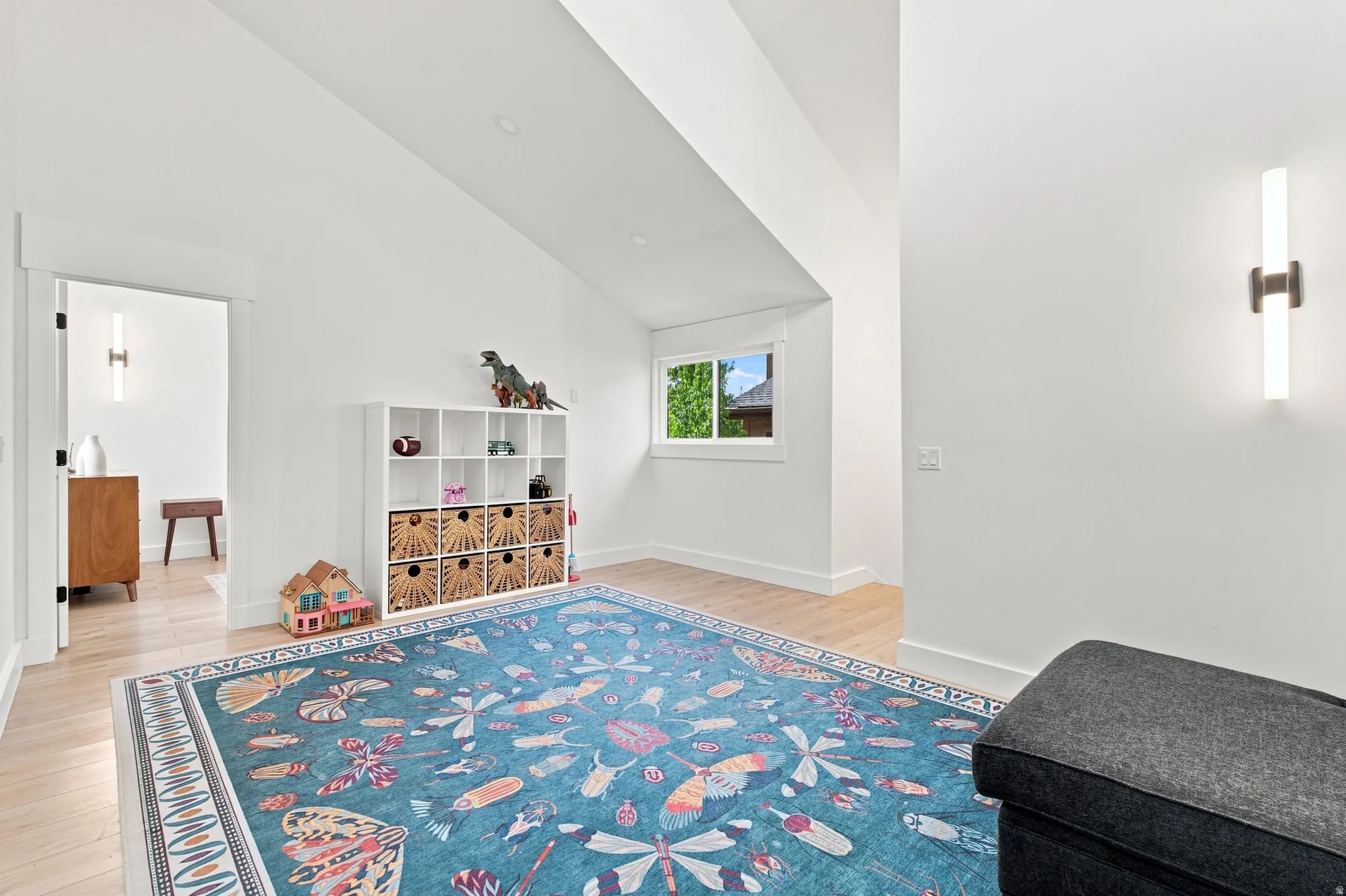 Vaulted ceiling, light wood-finish flooring, white walls, recessed ceiling lighting, and a single window