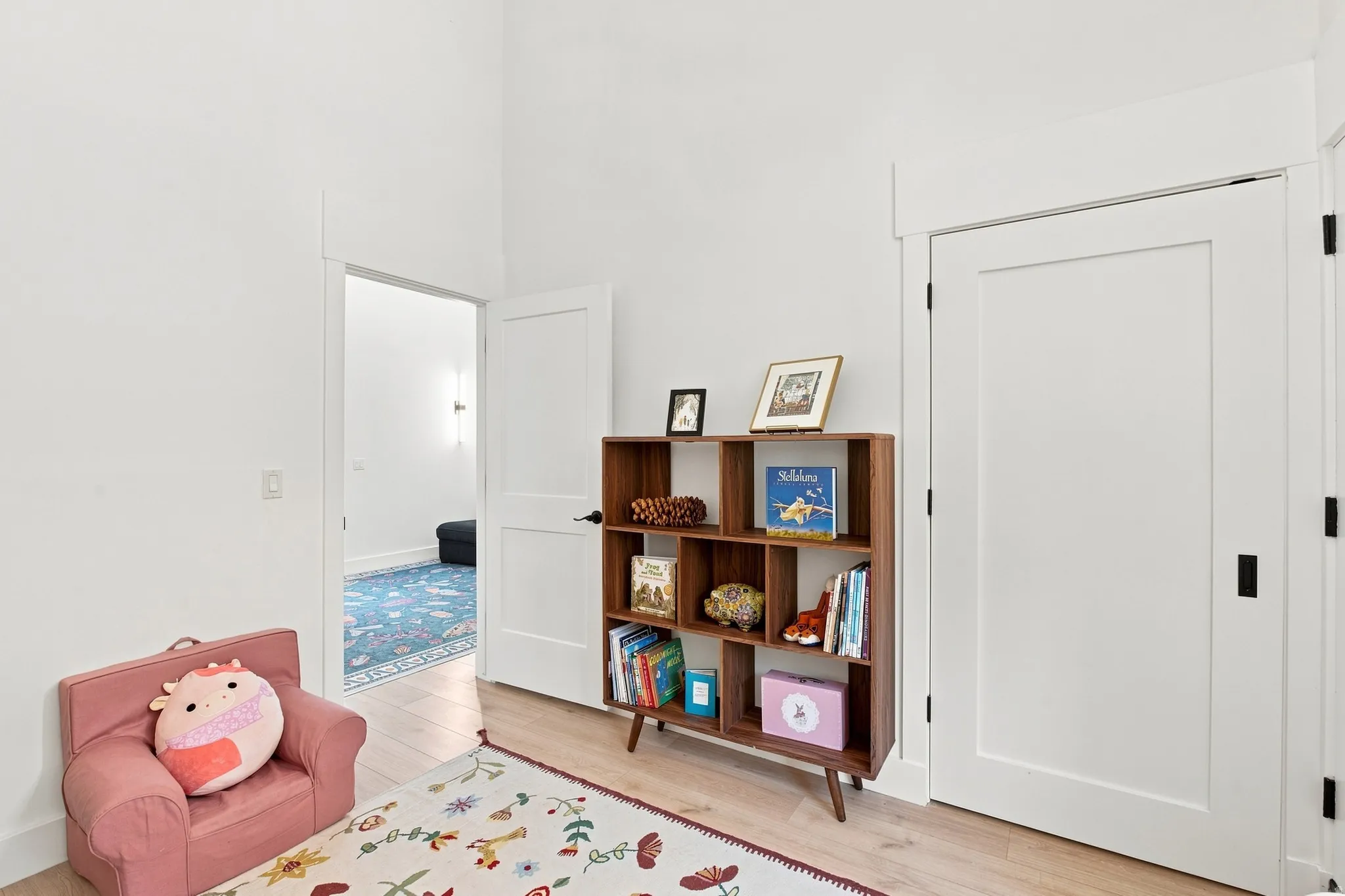 White flat panel doors with black hardware, light wood-finish flooring, and vaulted ceiling