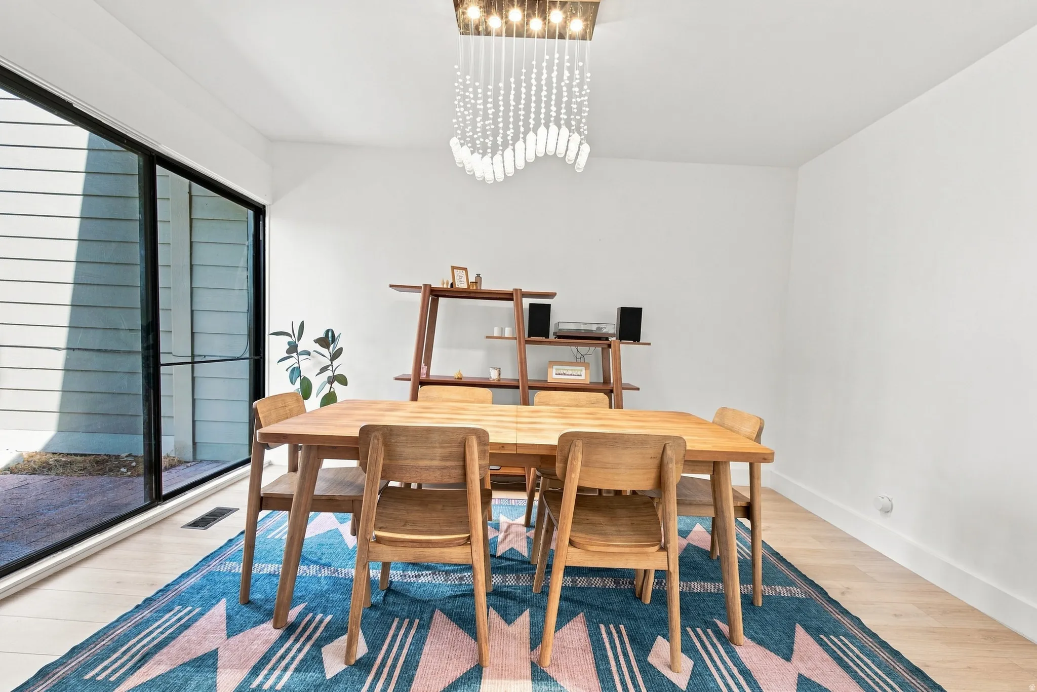 Wood-finish flooring, white walls, and a contemporary linear chandelier with cascading details