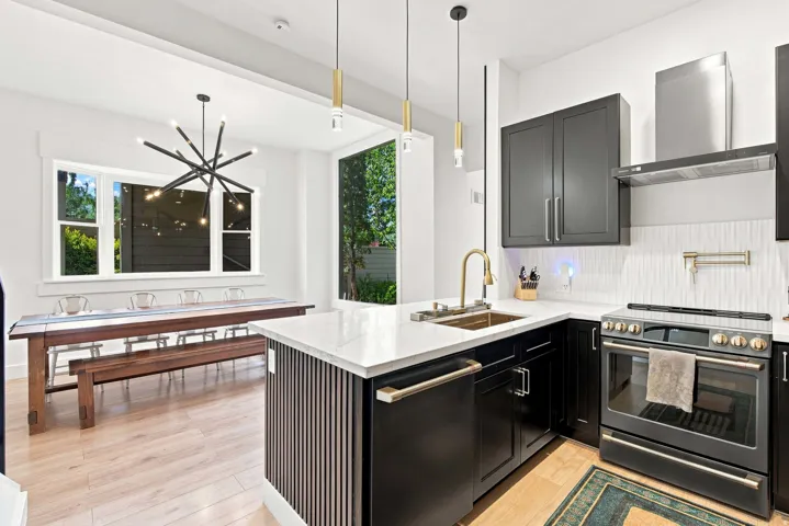 Kitchen featuring a corner sink with a brass faucet, white countertops, and black cabinetry