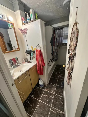 Bathroom featuring a single vanity with a laminate countertop, a built-in tub with shower, and tile flooring