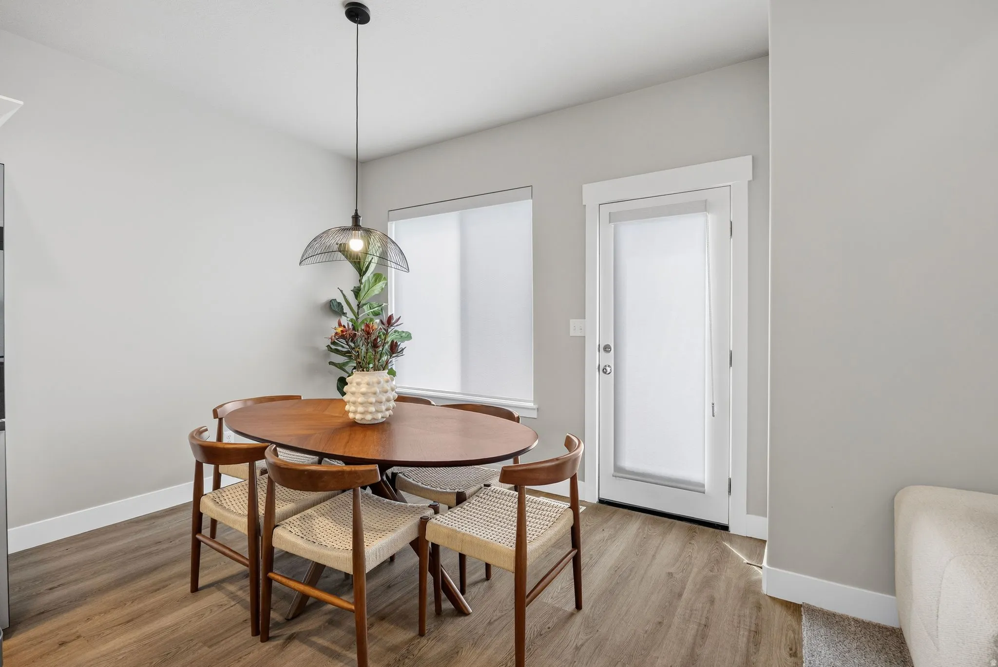 Wood-finish flooring, white baseboards, and a glass-paneled door with white trim