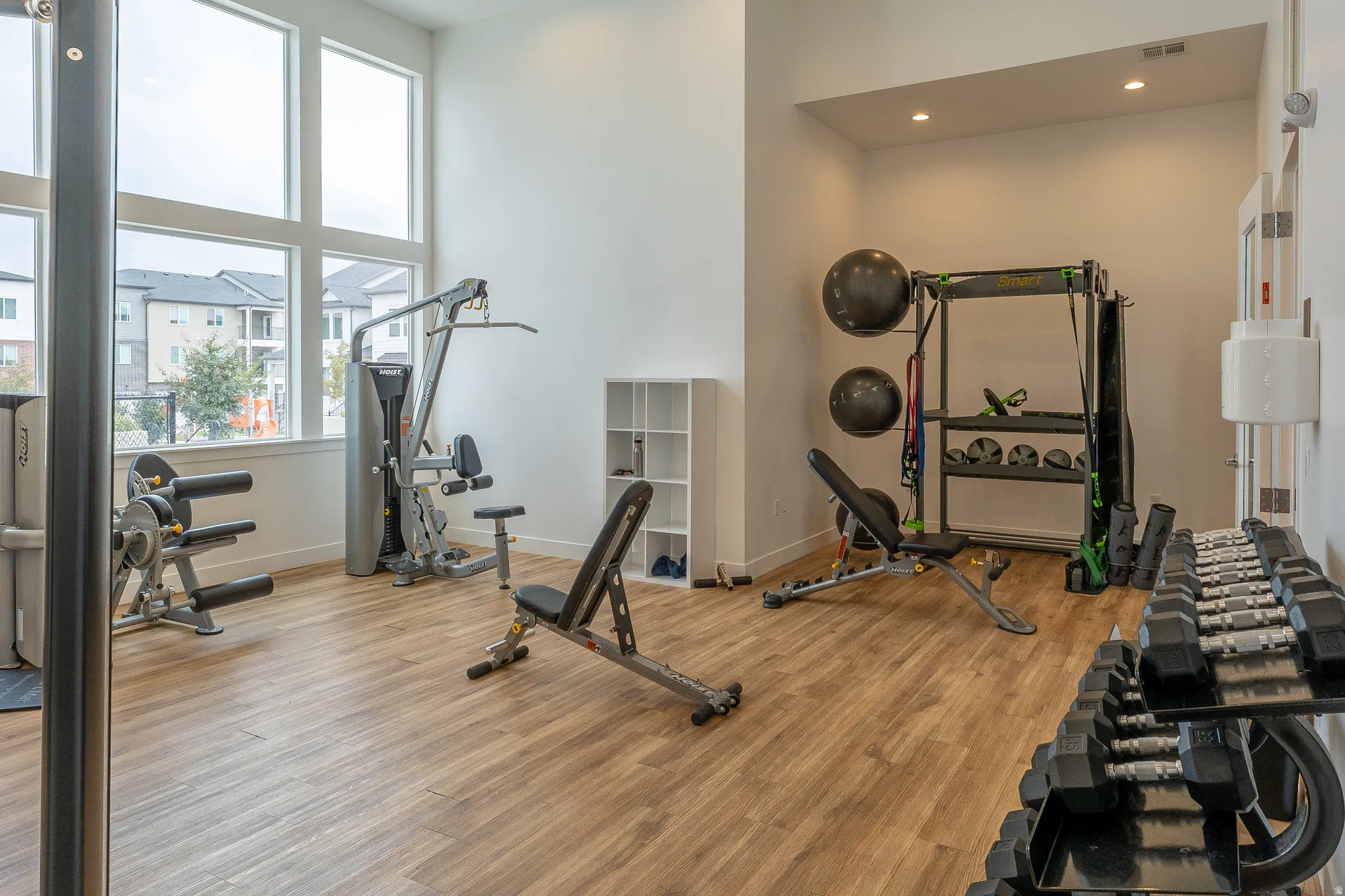 Fitness center featuring wood-finish flooring, high ceilings, large windows, and recessed lighting