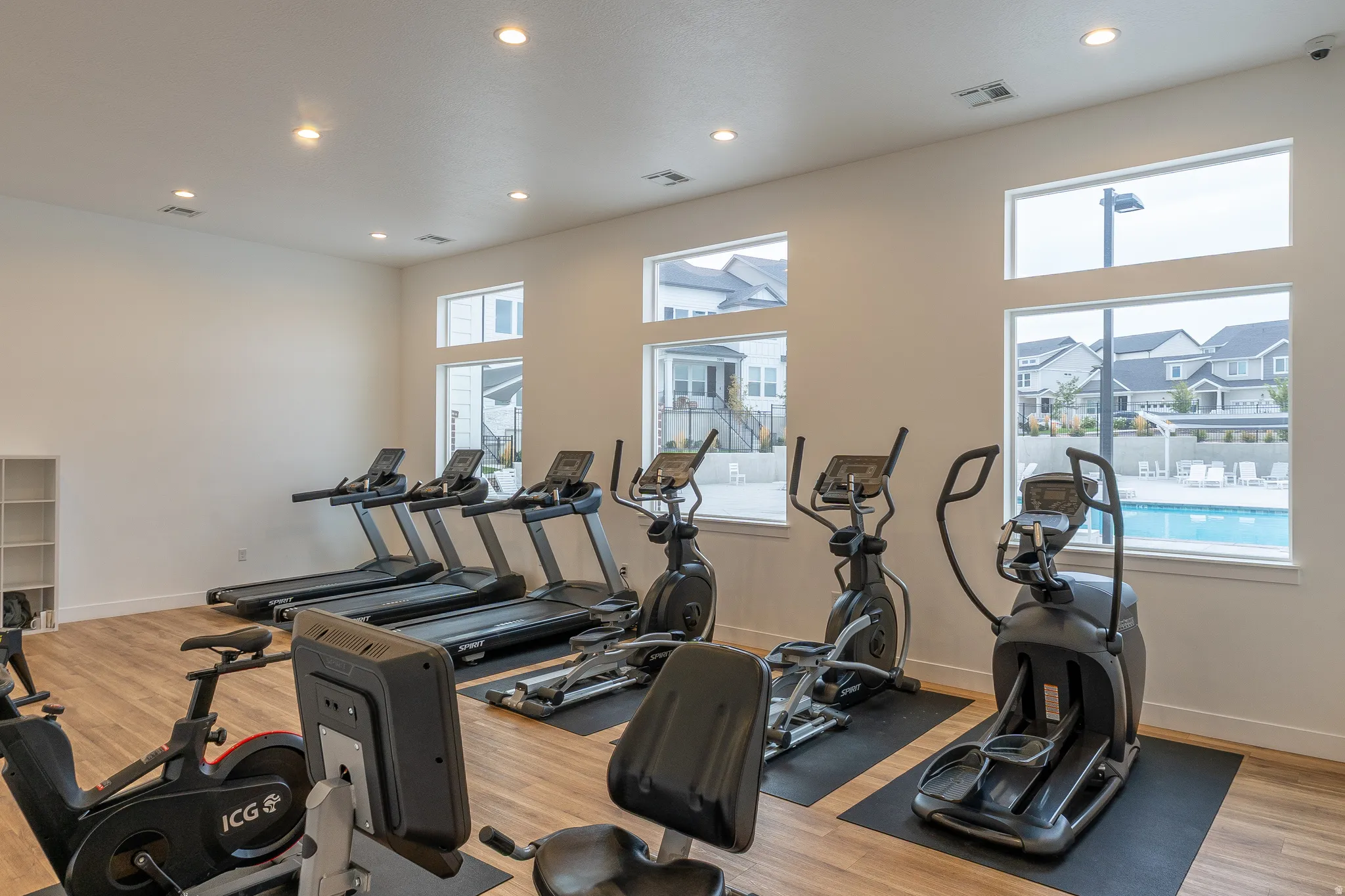 Fitness room featuring wood-finish flooring, recessed lighting, and multiple windows