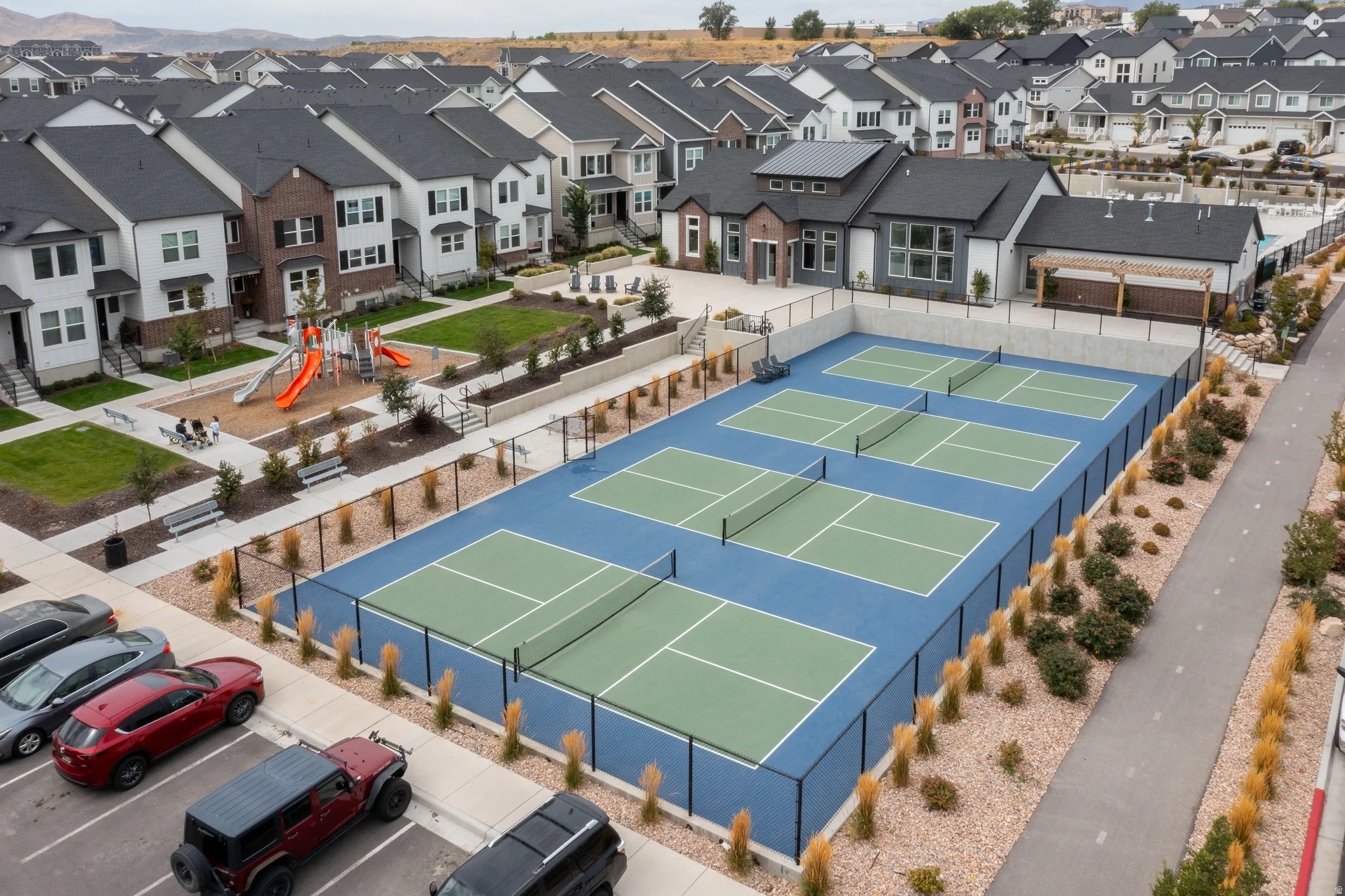 Four pickleball courts with perimeter fencing, a community playground, and a paved walking path