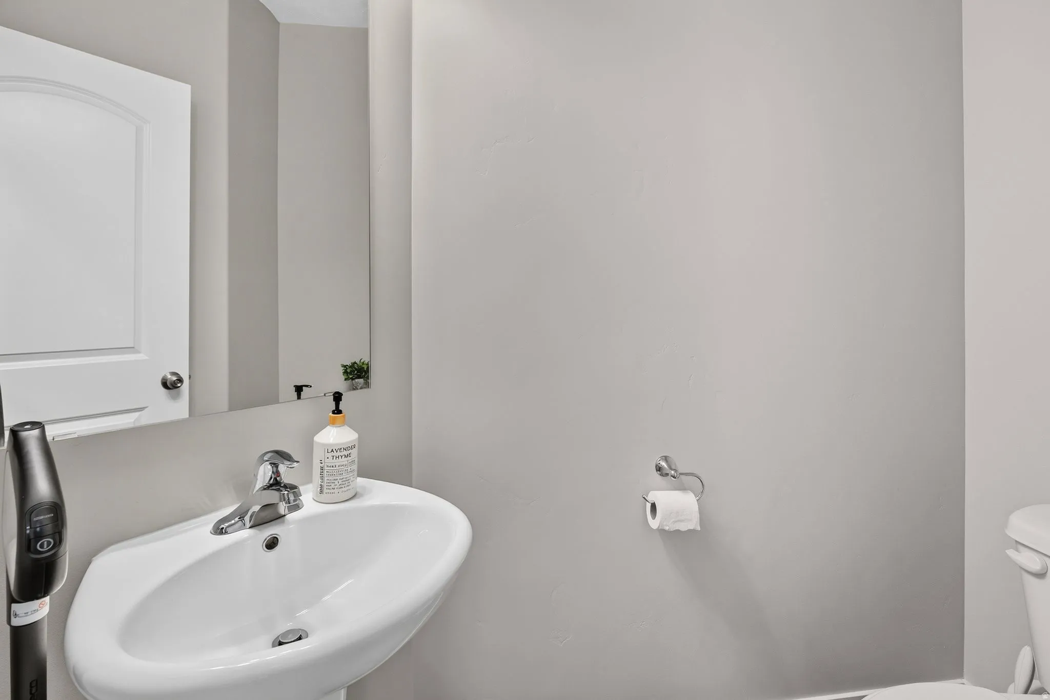 Pedestal sink with chrome fixtures and a wall-mounted mirror