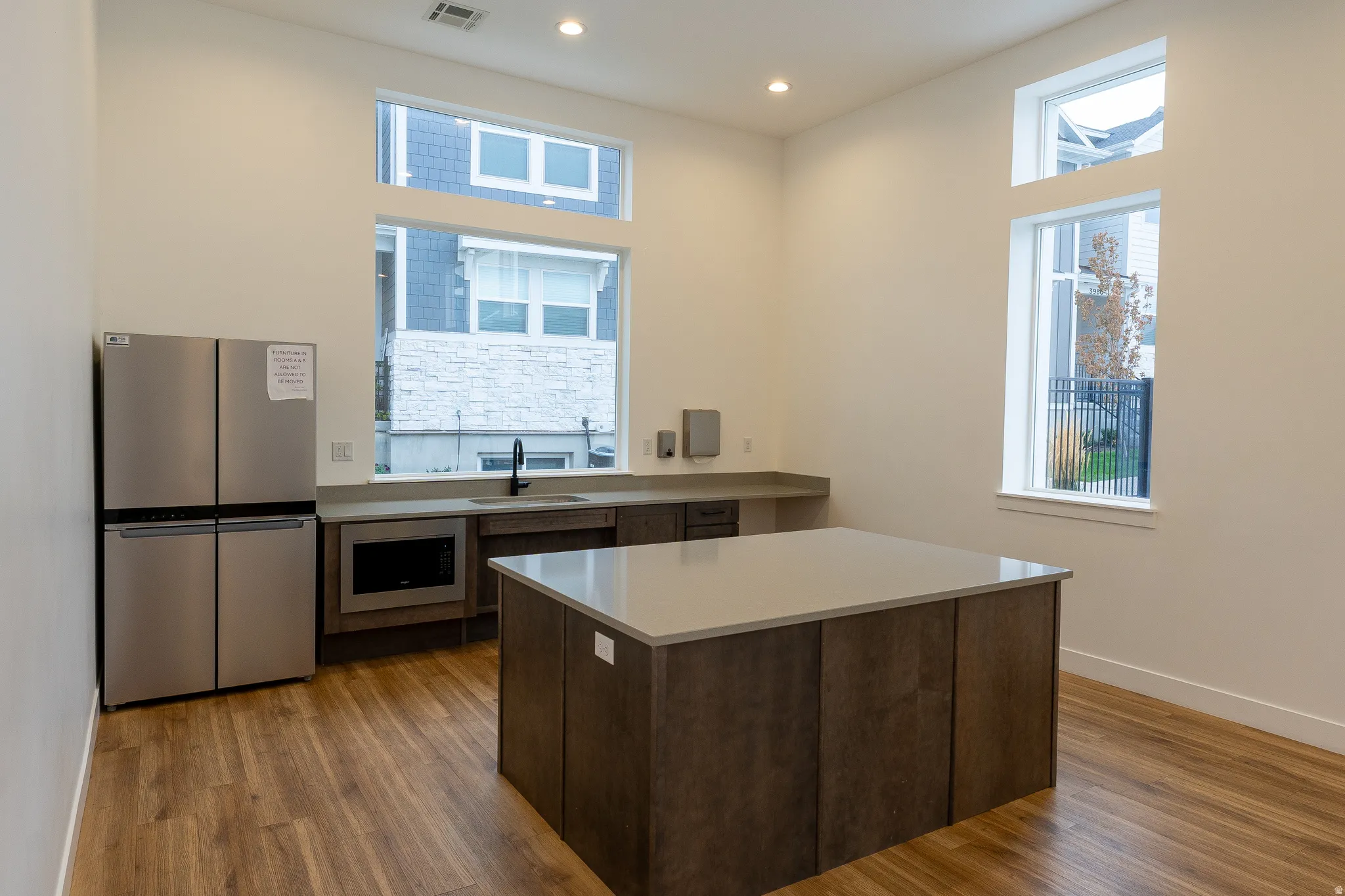 Wood-finish flooring, recessed lighting, and a stainless steel refrigerator
