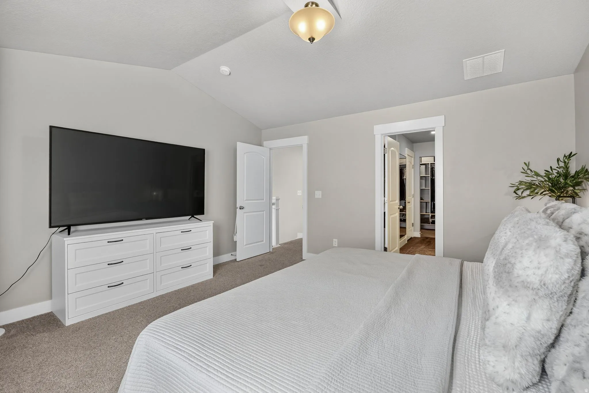 Vaulted ceiling, recessed lighting, neutral wall tones, carpet flooring, and a ceiling-mounted light fixture