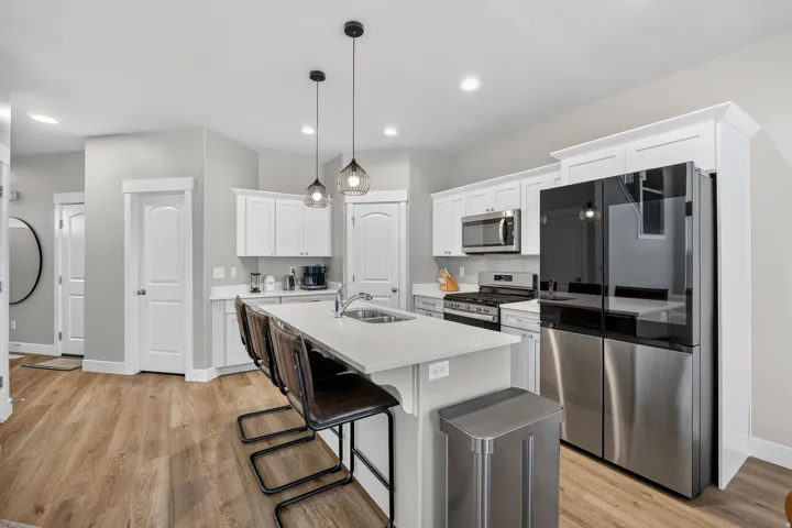 Kitchen with a large island, white cabinetry, integrated stainless steel appliances, and wood-finish flooring