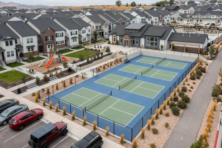 Four pickleball courts with perimeter fencing, a community playground, and a paved walking path
