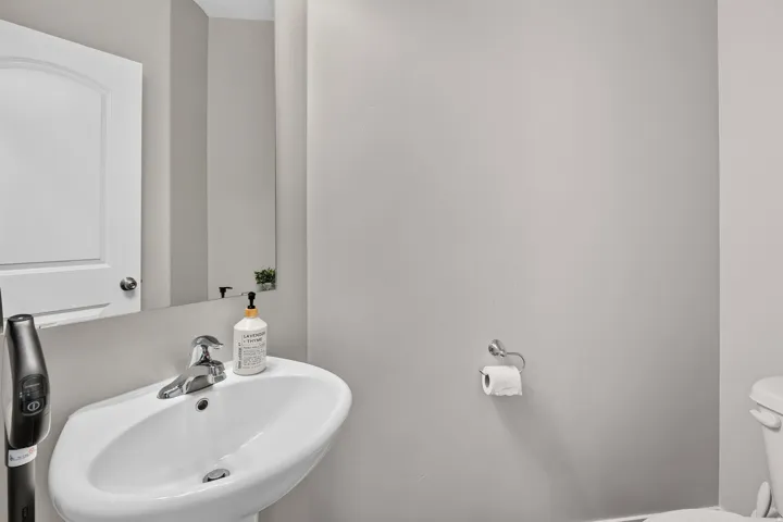 Pedestal sink with chrome fixtures and a wall-mounted mirror