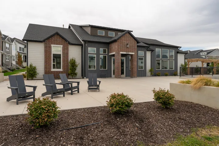 Contemporary architectural style with brick and siding facade, large window arrays, dark shingled roof, and an expansive concrete patio
