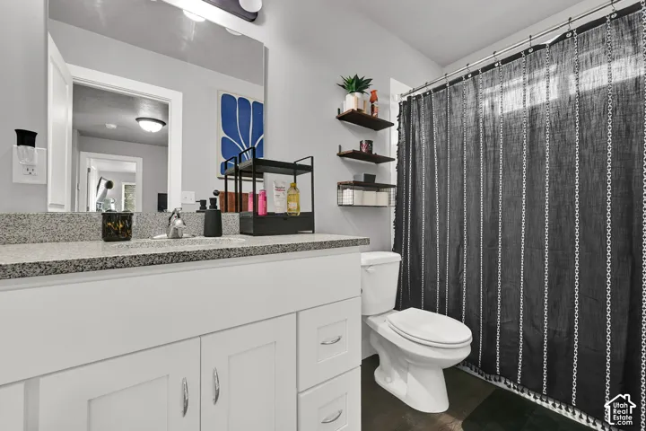 White vanity with a speckled countertop and single basin sink