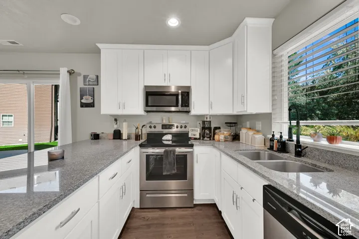White shaker cabinetry, stainless steel appliances, dual basin undermount sink, granite-style countertops, and wood-finish flooring