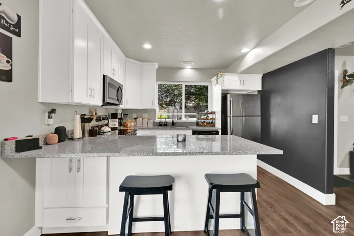 White upper cabinetry, dark wood-finish flooring, recessed lighting, white lower cabinetry, and a light-colored countertop