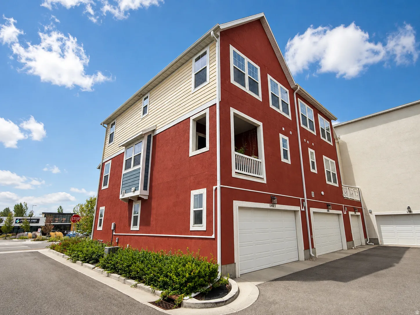 Multi-level exterior with red stucco and beige siding
