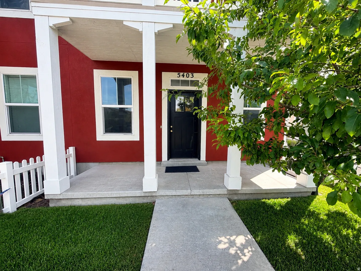 Red exterior with white trim, white porch columns, concrete walkway, concrete porch, and a black front door