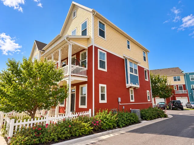 Multi-level exterior featuring a covered porch, white picket fence, mature landscaping, and a bay window detail