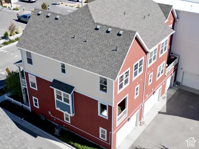 Three-story exterior featuring multi-toned siding, asphalt shingle roofing, multiple balconies with railings, and attached garage bays