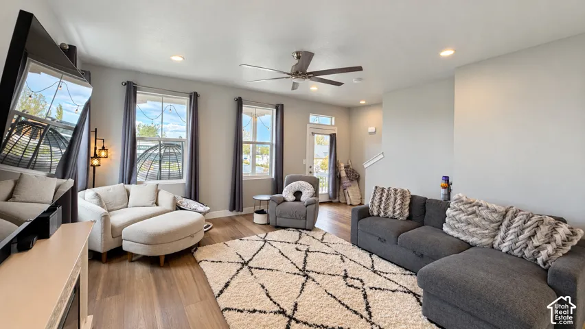 Spacious living area featuring wood-finish flooring, two large windows, recessed lighting, and a ceiling fan