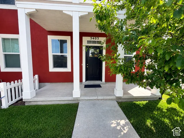 Red exterior with white trim, white porch columns, concrete walkway, concrete porch, and a black front door